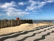 Coast Of Tramandaí Beach With A Wooden Fence Close To The Sea And A Copacabana Style Sidewalk Over The Sand. Southern Brazil.