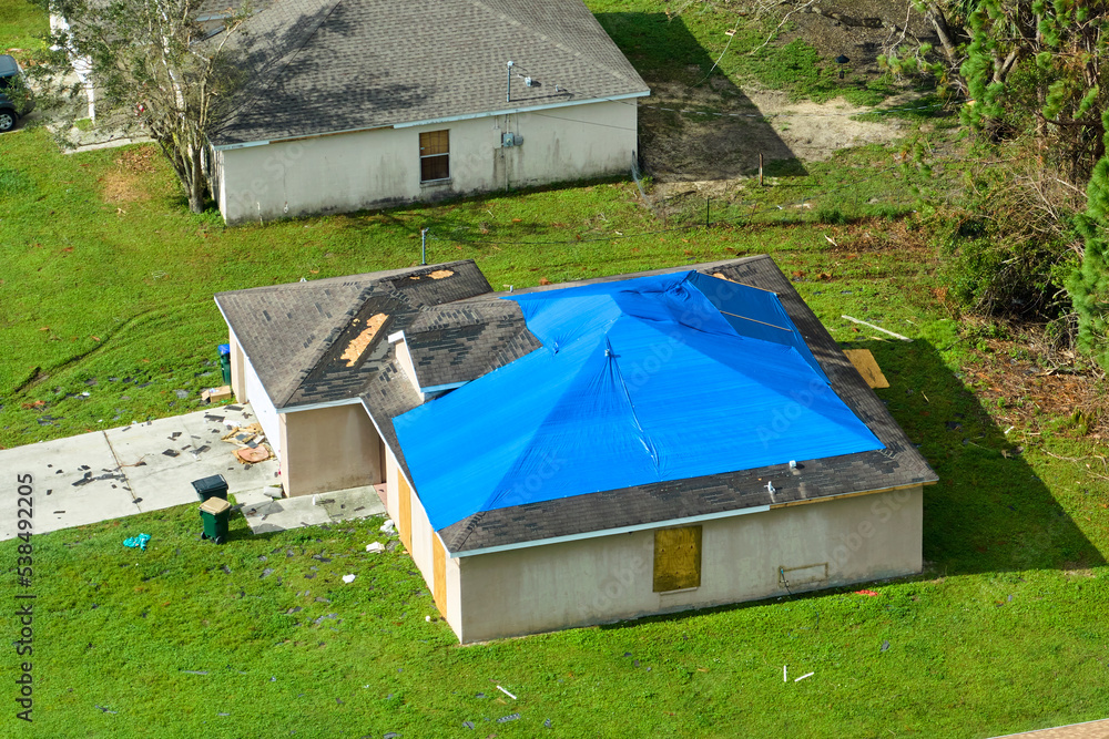 Top view of leaking house roof covered with protective tarp sheets