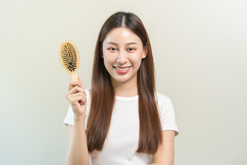 Health hair care, smile beautiful asian woman hand in holding hairbrush and brushing, combing her long straight hair in the morning routine after salon treatment, hairstyle. Isolated on background.