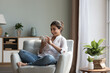 © fizkes - Happy Indian woman resting on cozy chair with smarthome, share messages to friend in social networks smile enjoy free time on internet. E-dating apps services for singles, electronic shopping at home