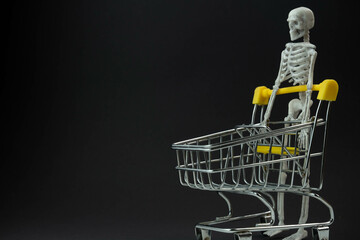 Wall Mural - a skeleton carries an empty cart from a supermarket on a black background, the concept of shopping sales in honor of the Halloween holiday