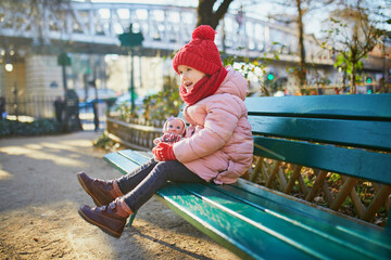 Wall Mural - Happy preschooler girl sitting on the bench on a street of Paris, France