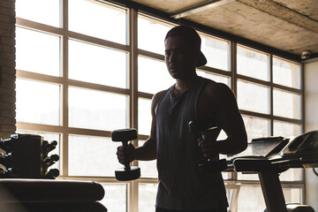 Poster - Muscular young male athlete performs exercises with dumbbells. Strength training in the gym