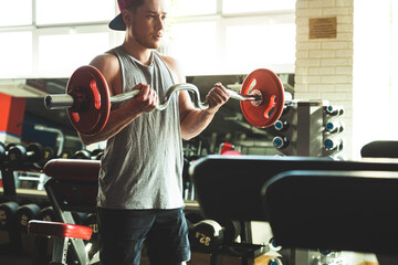 Poster - Young active muscular man performs exercises with a barbell in the gym. Power training