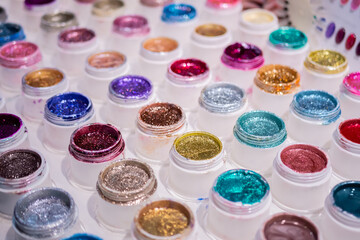 Canvas Print - Colorful makeup glitters in plastic cosmetic jars in row on counter for sale in cosmetics shop, tradeshow. Glamour, fashion, make up, beauty and skincare concept