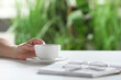 © New Africa - Woman holding cup of coffee at white table indoors, closeup