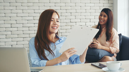 Wall Mural - Two businesswomen team meeting using laptop at company office desk. Two young Female freelance reading financial graph charts Planning analyzing marketing data. Asian people team working office firm.