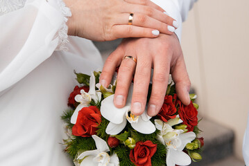 Wall Mural - hands of the newlyweds on a wedding bouquet of roses and orchids. concept for agencies