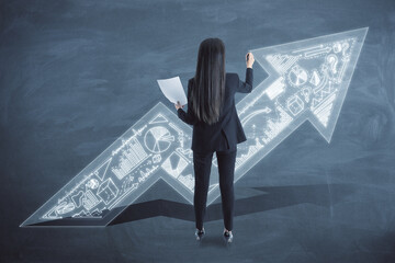 Back view of businesswoman with upward business arrow sketch drawing on chalkboard wall background. Success, finance and productivity concept.