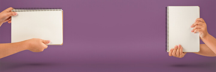 Wall Mural - Notepad in hand. Blank notepad in the hands on a violet background. Hands hold a book without text. The girl is holding a book with an empty cover.