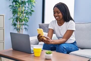 Wall Mural - Young african american woman using laptop and smartphone at home