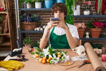 Wall Mural - Young blond man florist make photo to flower by smartphone at flower shop