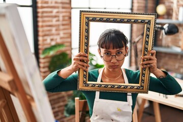 Sticker - Young beautiful woman sitting at art studio with empty frame skeptic and nervous, frowning upset because of problem. negative person.