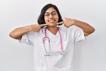 Poster - Young hispanic doctor woman wearing stethoscope over isolated background smiling cheerful showing and pointing with fingers teeth and mouth. dental health concept.