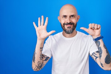 Poster - Hispanic man with tattoos standing over blue background showing and pointing up with fingers number six while smiling confident and happy.