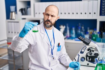 Sticker - Young bald man scientist holding test tube writing on notebook at laboratory