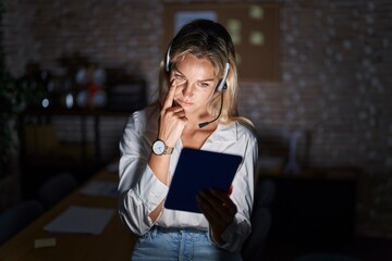 Poster - Young blonde woman working at the office at night pointing to the eye watching you gesture, suspicious expression