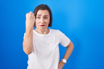 Poster - Middle age hispanic woman standing over blue background doing italian gesture with hand and fingers confident expression