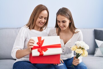 Canvas Print - Two women mother and daughter surprise with birthday gift and flowers at home