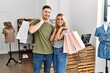 © Krakenimages.com - Young hispanic customer couple smiling happy holding shopping bags at clothing store.