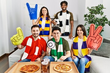 Wall Mural - Group of young people wearing team scarf cheering football game looking positive and happy standing and smiling with a confident smile showing teeth