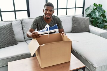 Poster - Young african american man smiling confident unpacking sneakers at home