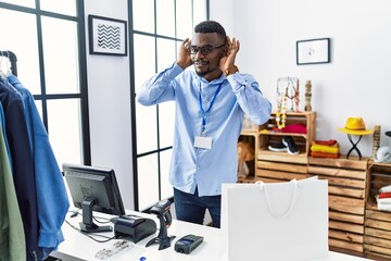 Wall Mural - Young african man working as manager at retail boutique trying to hear both hands on ear gesture, curious for gossip. hearing problem, deaf