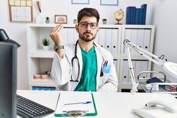 Sticker - Young man with beard wearing doctor uniform and stethoscope at the clinic doing italian gesture with hand and fingers confident expression