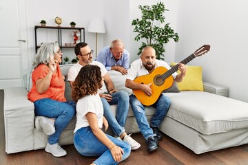 Poster - Group of middle age friends having party playing classical guitar sitting on the sofa at home.