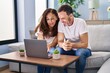 © Krakenimages.com - Middle age man and woman couple using laptop sitting on sofa at home