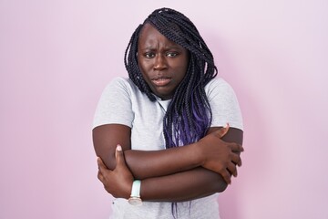 Canvas Print - Young african woman standing over pink background shaking and freezing for winter cold with sad and shock expression on face