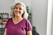 © Krakenimages.com - Middle age grey-haired woman smiling happy standing at home.
