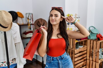 Sticker - Young brunette woman holding shopping bags at retail shop smiling pointing to head with one finger, great idea or thought, good memory