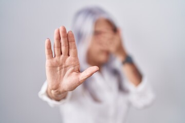 Canvas Print - Middle age woman with tattoos wearing glasses standing over white background covering eyes with hands and doing stop gesture with sad and fear expression. embarrassed and negative concept.