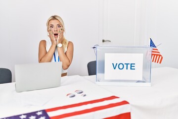 Canvas Print - Young caucasian woman at america political campaign election afraid and shocked, surprise and amazed expression with hands on face