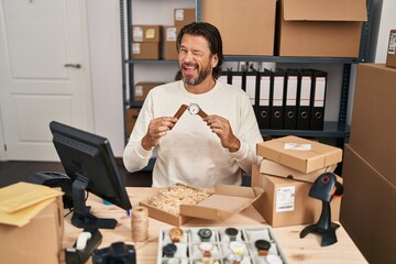 Canvas Print - Handsome middle age man working at small business ecommerce repairing watches winking looking at the camera with sexy expression, cheerful and happy face.