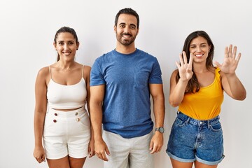 Canvas Print - Group of young hispanic people standing over isolated background showing and pointing up with fingers number nine while smiling confident and happy.