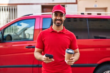 Canvas Print - Young hispanic man courier using smartphone drinking coffee at street