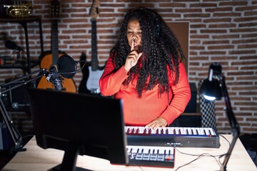 Sticker - Plus size hispanic woman playing piano at music studio asking to be quiet with finger on lips. silence and secret concept.