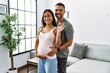 © Krakenimages.com - Latin man and woman couple hugging each other holding key of new house expecting baby at home