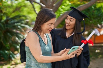 Poster - Two women mother and graduated daughter using smartphone at park