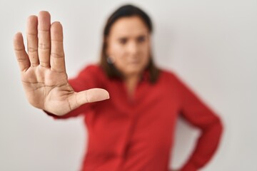 Sticker - Hispanic mature woman standing over white background doing stop sing with palm of the hand. warning expression with negative and serious gesture on the face.