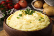 Bowl of freshly cooked mashed potatoes with parsley on wooden table, closeup