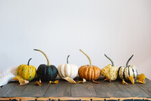 Multicolored Pumpkins And Dry Autumn Leaves On Wooden Background. Top View For Autumn, Fall, Thanksgiving Concept. .Autumn Background