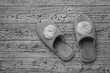 Black and white photo of house slippers on a wooden background. The concept of home shoes.