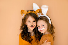 Children With Painted Faces In Rabbit And Tiger Costumes Are Hugging And Smiling Sweetly. The Old New Year Meets The New One. Stage Animal Costumes.
