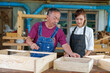 © ND STOCK - Tutor With Female Carpentry Student In Workshop Studying For Apprenticeship At College ,Teacher explaining a structure students while standing in a woodwork class