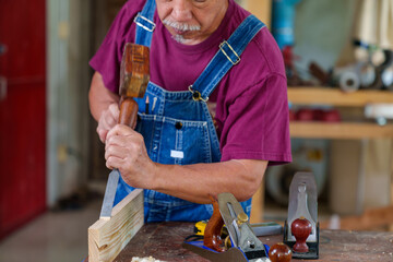 Wall Mural - carpenter hands working with a chisel and hammer on wooden workbench