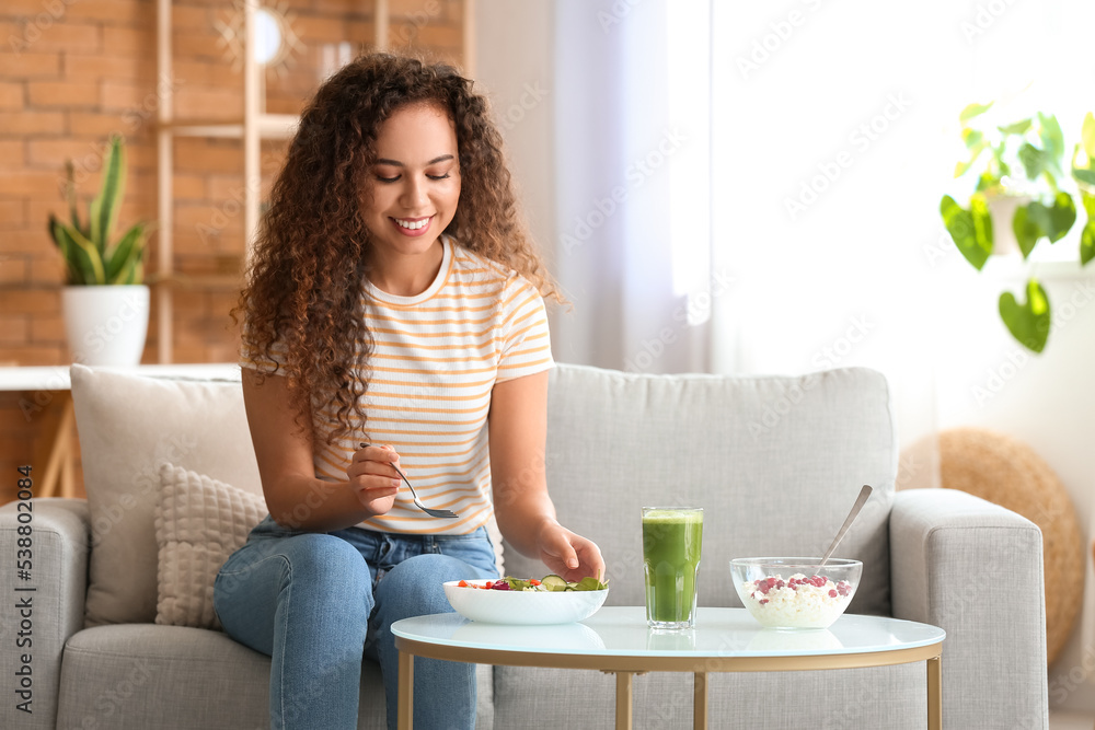 Young African-American woman eating healthy food at home. Diet concept
