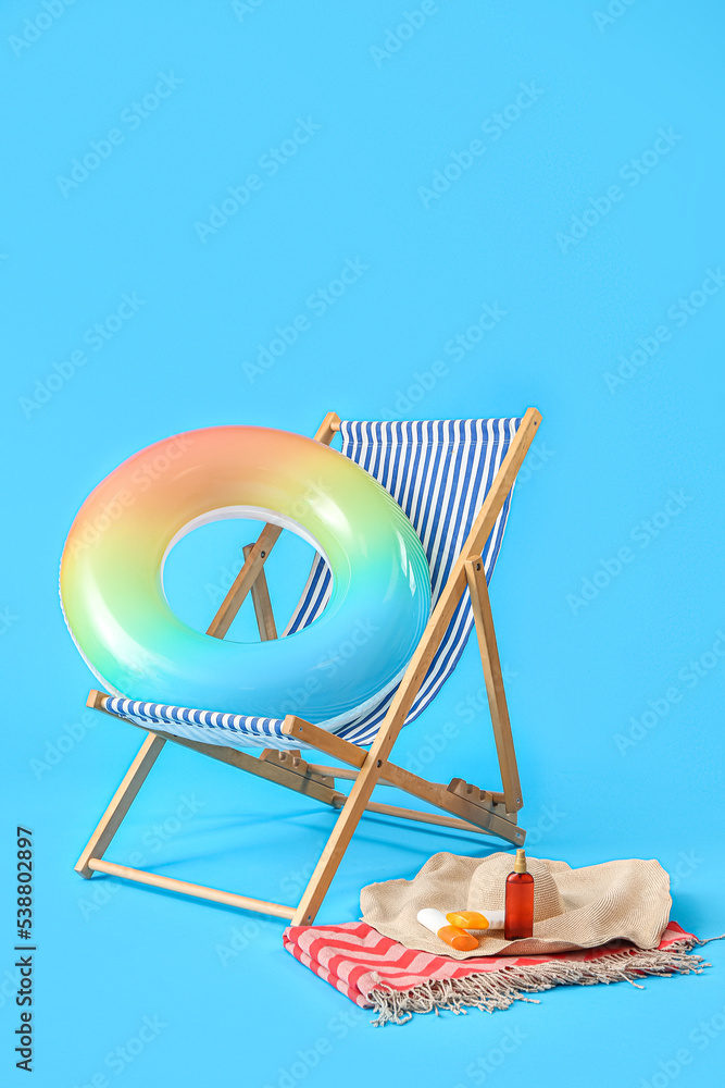 Deck chair and beach accessories on light blue background